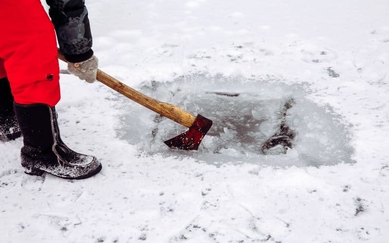 cutting ice fishing hole with an ax